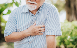 Senior man slightly bent over clutching at heart chest