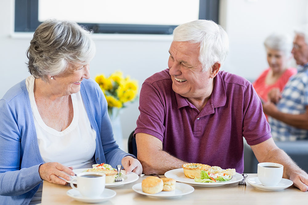 Happy senior couple smiling and having lunch together in independent living community