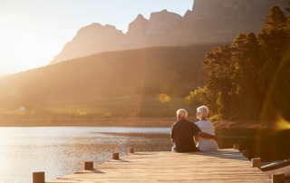 Senior couple enjoying retirement sitting on the dock at a lake at sunset