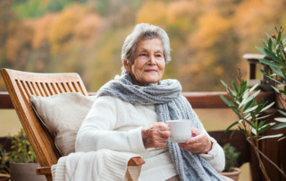 Senior woman sitting outside relaxing in chair with cup of coffee