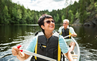 Senior couple traveling during retirement, in canoe on river