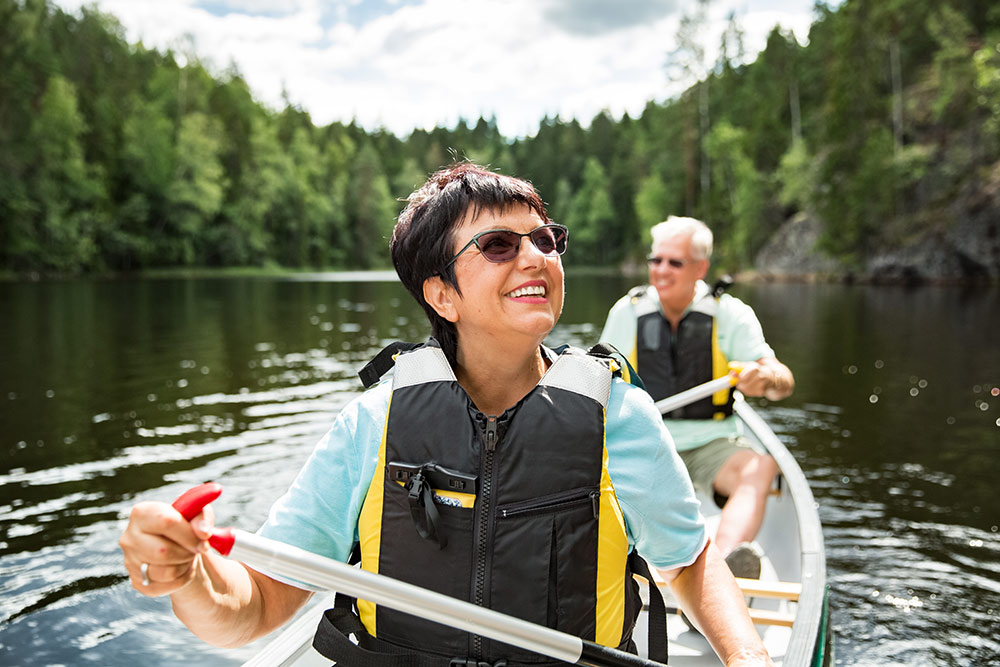 Senior couple traveling during retirement, in canoe on river