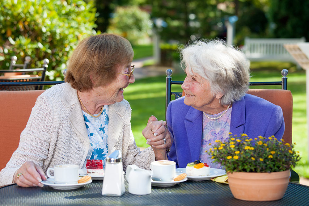 Two senior women having lunch and looking at each other smiling