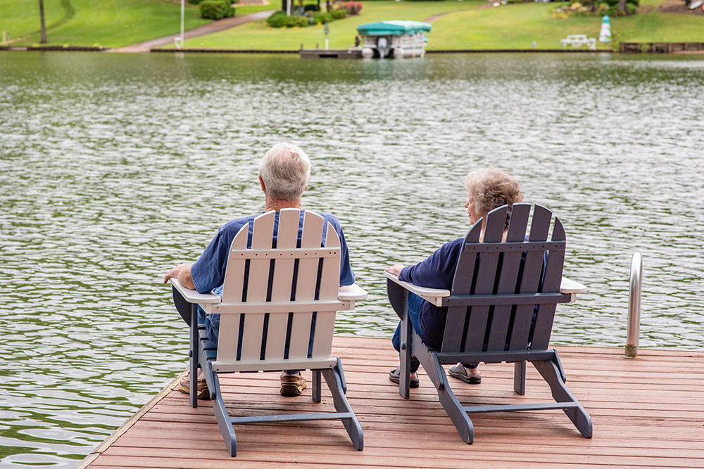 Senior couple sitting in chairs on dock by lake